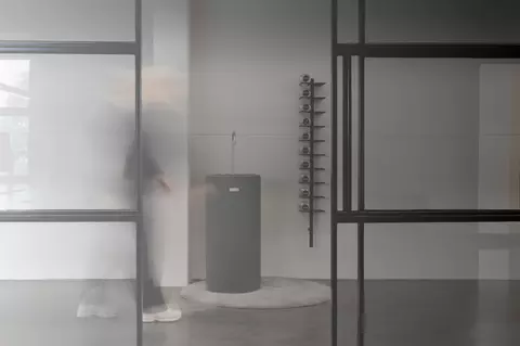 Wasserspender im Büro hinter Glasscheiben und mit Flaschenregal